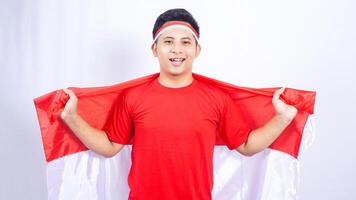 Indonesian Man Holding Red and White Indonesia Flag Behind Back on White Background photo