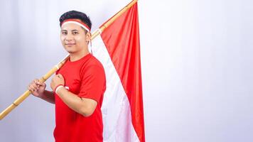Portrait of Indonesian Man with Red and White Flag Showing Salute Pose on White Background photo