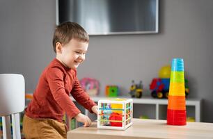 A cute little toddler boy of two years old plays with multi-colored balls and sits at a children's table in his room. Tactile sensory balls. Educational toys for children photo