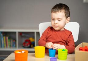 A beautiful little boy of two or three years old sits at a table photo
