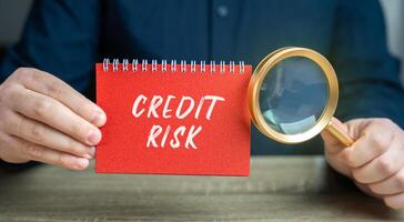 Credit risk concept. Financial loss resulting from a borrower's failure to repay a loan. Business and finance. Notepad and magnifying glass in the hands of a businessman photo