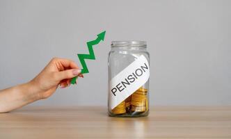 Bank of coins and the inscription Pension and green arrow up. Increase in pension payments and retirement interest rates. Business and finance concept. photo