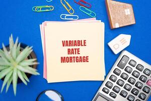 Variable rate mortgage concept. Type of home loan in which the interest rate is not fixed. Real estate, business and finance concept. Miniature houses, magnifying glass, calculator and notes photo