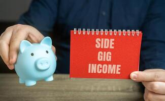 Side gig income refers to earnings generated from work or activities done in addition to a person's primary job. Notebook and piggy bank in male hands. business and finance concept photo