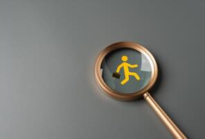 Magnifying glass and running man with briefcase in focus. Migration of labor. Flight of businesses and investors. Corporate relocation, skilled worker shortages. Talent search in job markets. photo