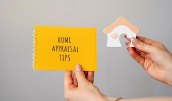 Home Appraisal tips concept. Strategies and best practices homeowners can use to maximize the assessed value of their property during a professional appraisal. Notebook and house in hands photo