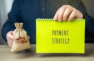 Payment strategy concept. Planned approach to managing financial transactions, ensuring timely and efficient payments and optimizing cash flow. Notepad in the hands of a businessman and a money bag photo