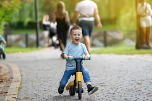 A cute happy caucasian toddler boy of three or four years old rides photo