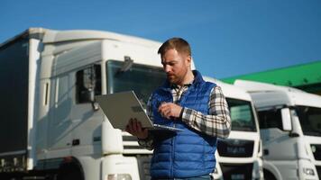 A supervisor uses a walkie talkie and laptop to provide loading instructions at a truck parking lot video