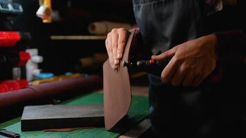 A craftsman uses a rotary tool to polish leather edges, achieving a smooth, professional finish video