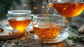 A warm cup of tea being poured into a glass cup, with a cozy wooden table and festive decorations in the background photo