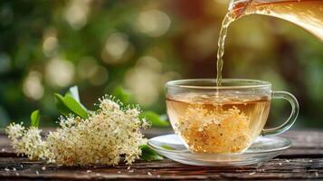 A serene scene of herbal tea being poured into a glass cup, surrounded by fresh flowers and greenery photo