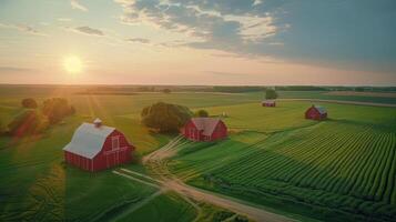 Aerial view of serene farmland at sunset with red barns and lush green fields in background photo