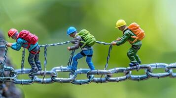 Miniature figures of climbers navigating a chain against a blurred green background photo