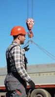 A foreman in a hard hat signals to a crane operator while lifting a concrete slab at a busy construction site video