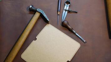 A set of leatherworking tools and perforated templates on a brown leather sheet video