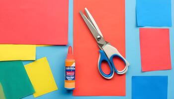 Scissors, glue and paper on a blue background photo