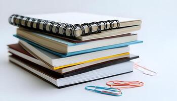 A stack of books with a paper clip and a pen photo