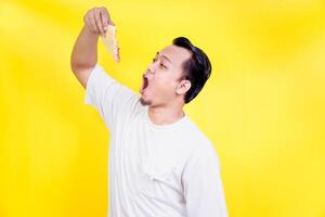 An asian man eagerly prepares to bite into a delicious sandwich against a vibrant yellow backdrop. international foods day concept photo