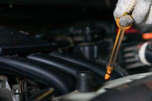 A mechanic checks oil levels using a dipstick in a car engine compartment. photo