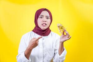 an asian woman in hijab holding and pointing of a piece of food photo