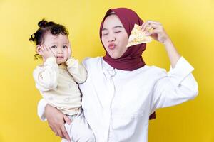 a woman in a hijab holding a child and holding a piece of pizza photo