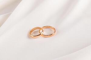 Two charming gold wedding rings on the soft surface of cream colored chiffon fabric. A copy of the space. wedding background. layout for design. photo