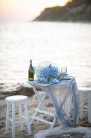 The sky and sea blend in deep blue tones as a romantic dinner unfolds, the clink of wine glasses echoing softly in the evening breeze. photo