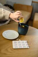 The child squeezes a lemon into a cup of tea, carefully pressing the juice out with both hands. photo