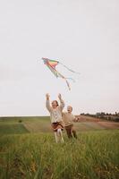The sky is bright with color as the kite glides, trailed by joyful, running children. photo