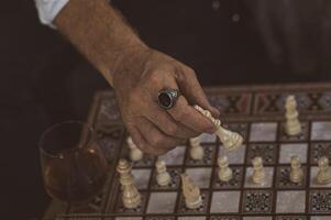 A calculated move his ringed hand shifts a piece with quiet confidence and sharp focus. photo
