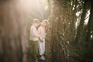 The forest glows with golden light as two young explorers study the creeping plants, mesmerized by natures quiet magic. photo