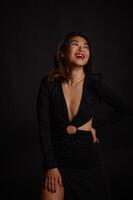 A captivating image of an Asian woman in a black dress, the studios dark setting adding sophistication. photo