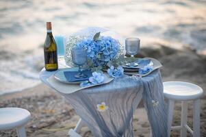 Two glasses of wine rest on a beautifully set table, the ocean stretching endlessly behind them, wrapped in the cool serenity of dusk. photo