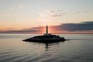 A lighthouse is on an island in the middle of the ocean photo
