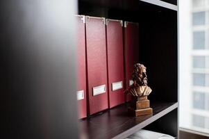 The contrast of modern office folders and an ancient Aristotle statue creates a unique atmosphere. photo