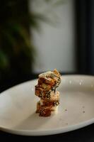 A beautifully plated eel sushi rests on a sleek dish, its glossy unagi sauce adding a rich, savory sheen to the tender fish. photo