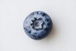 A blueberry is shown on a white surface photo