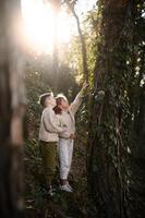 Amid the towering trees, they explore the twisting vines, their fingers brushing the rough bark in quiet fascination photo