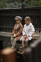 On a quiet countryside bridge, two kids share a baguette from a woven basket, lost in a moment of warmth and simplicity. photo