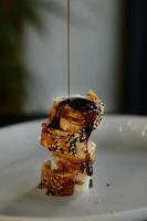A smooth stream of unagi sauce cascades over the sushi, coating the delicate eel in a glossy, savory-sweet glaze. photo