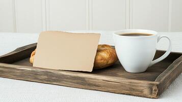Cozy setup featuring a cup of coffee, a pastry, and a blank kraft card on a rustic wooden tray. Perfect for personalization or messages photo