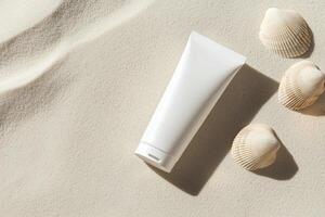 Flat lay of blank white skincare tube placed on soft sand with seashells, evoking beach vibes and summer skincare concepts photo