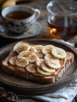 Peanut butter and banana toast with tea on a wooden plate photo