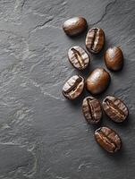 A captivating top view showcases rich, dark coffee beans artfully scattered across a sleek grey slate background, creating a perfect visual for coffee lovers and true enthusiasts everywhere photo