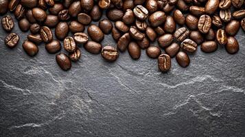 A stunning top view of coffee beans scattered on a grey slate background, showcasing their rich texture and inviting aroma. This image is perfect for coffee lovers and brewing enthusiasts photo