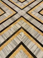 Various natural marble arrangements cut and shaped into chevron and arrow pattern, X shape pattern. Grey, yellow, and black marble combined and cut into X-shape chevron pattern. photo