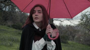 du froid femme avec rouge parapluie dans le Publique parc sur une nuageux journée video