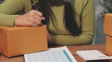 A woman is sitting at a table with a calculator and a box video