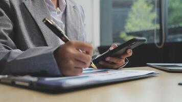 A business person is using a smartphone and pen to write on a piece of paper video
